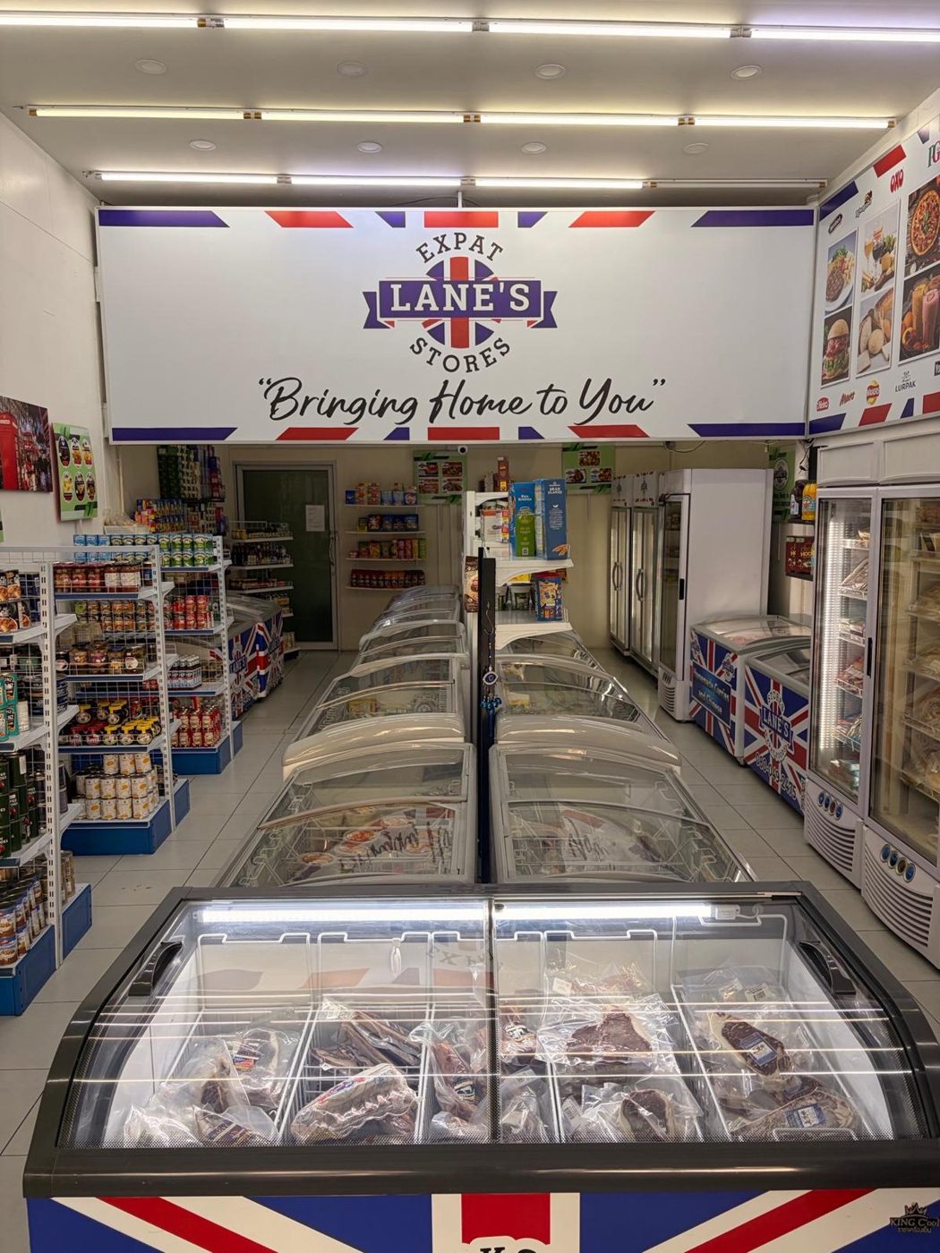 Inside Lane's Expat Stores with the Bringing Home to You sign above freezers of imported foods
